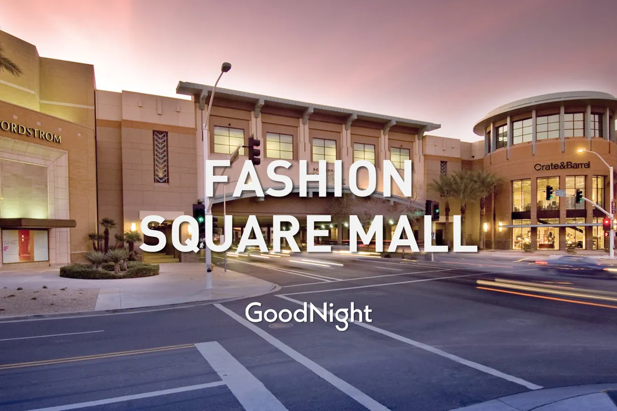 A stylish shopping district with recognizable storefronts like Nordstrom and Crate & Barrel, palm trees lining the street, and people out for a pleasant evening. The setting is lively yet relaxed, showcasing high-end retail options steps away.