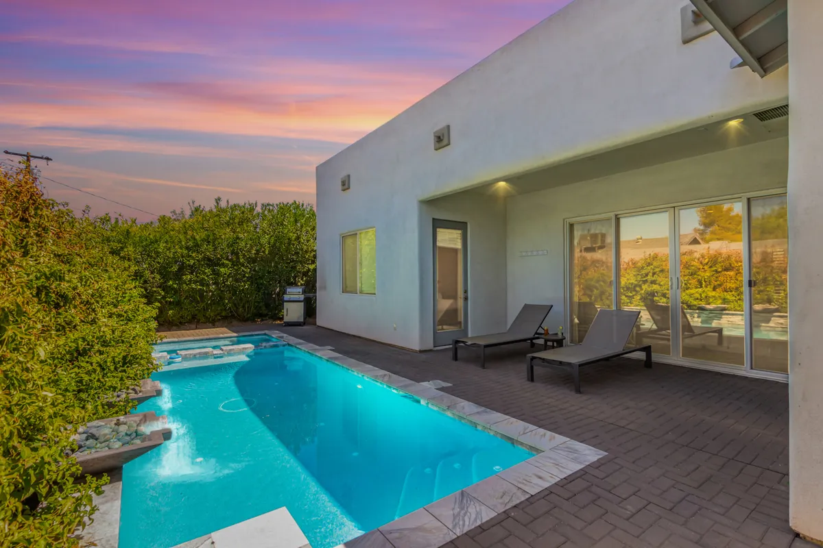 A tranquil, sunlit outdoor area featuring a sparkling swimming pool, comfortable lounge chairs, and a well-appointed patio. The setting is ideal for al fresco dining, group gatherings, and enjoying Arizona’s warm evenings.