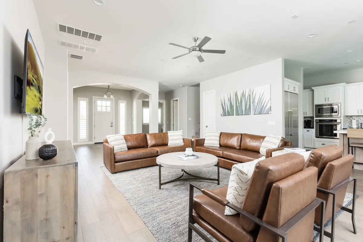 A stylish living area with plush leather sofas, a round coffee table, and elegant wall art, bathed in soft lighting. The decor is contemporary, and the setting feels both welcoming and upscale, ideal for relaxing or socializing.
