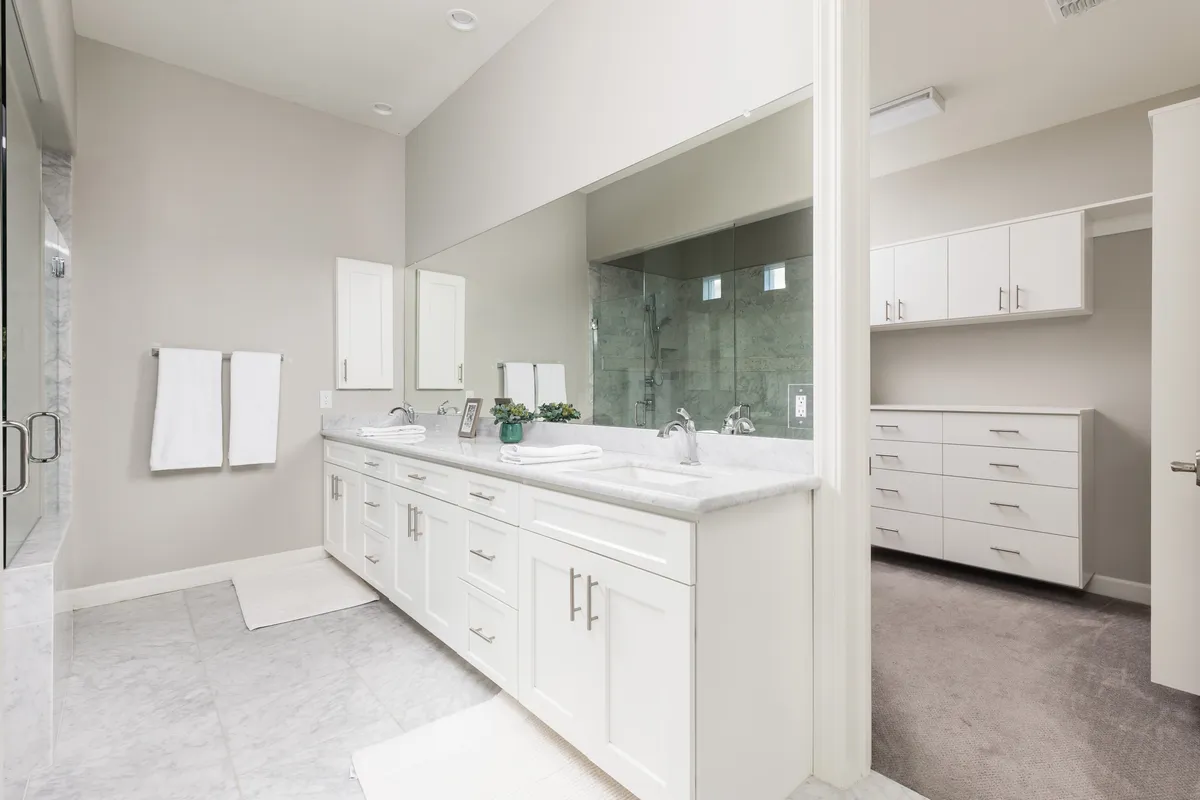 A spacious, modern bathroom with a double vanity, a large mirror, glass shower enclosure, and a neutral color palette. The room feels organized, serene, and perfect for morning routines or unwinding after a busy day.